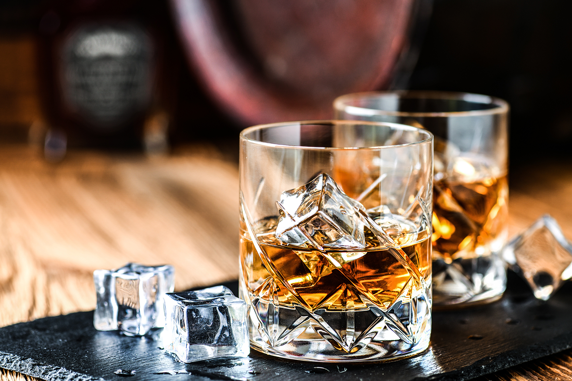 Glass of whiskey with ice cubes on black stone table. Side view with copy space alcohol concept. Glass of whiskey with ice cubes on black stone table. Side view with copy space alcohol concept.
