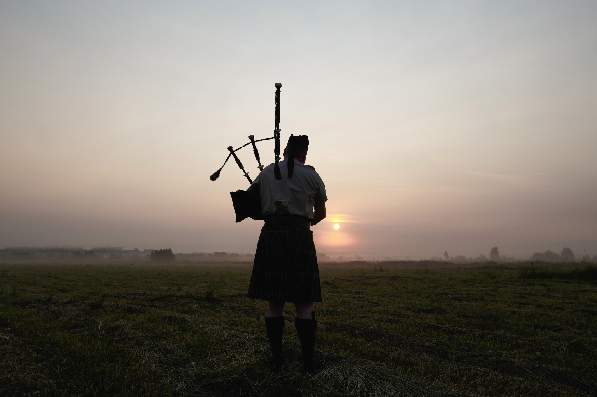 A man playing a bagpipe during a Scottish sunset. A man playing a bagpipe during a Scottish sunset.