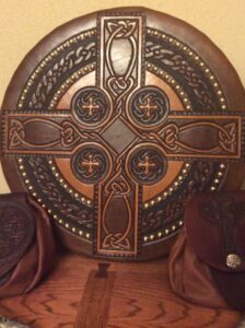 wooden Celtic cross adorned with leather A wooden celtic cross adorned with leather pouches, providing the perfect Scottish Targe accessory.