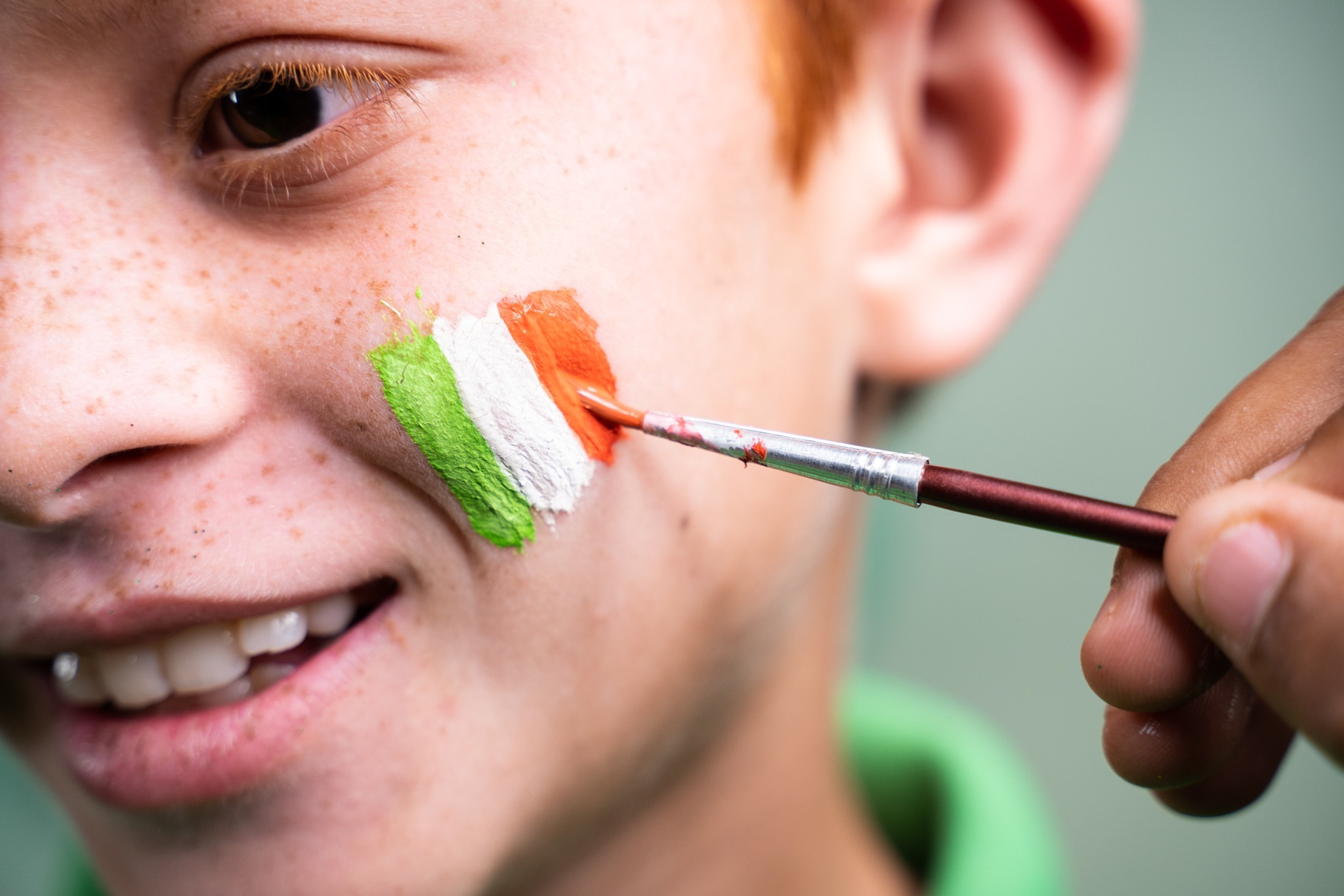 A red-headed child having the Irish flag painted on his cheek. A red-headed child having the Irish flag painted on his cheek.