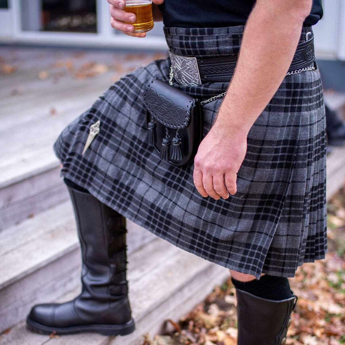 A man wearing a kilt, sporran, and boots while holding a beer. A man wearing a kilt, sporran, and boots while holding a beer.