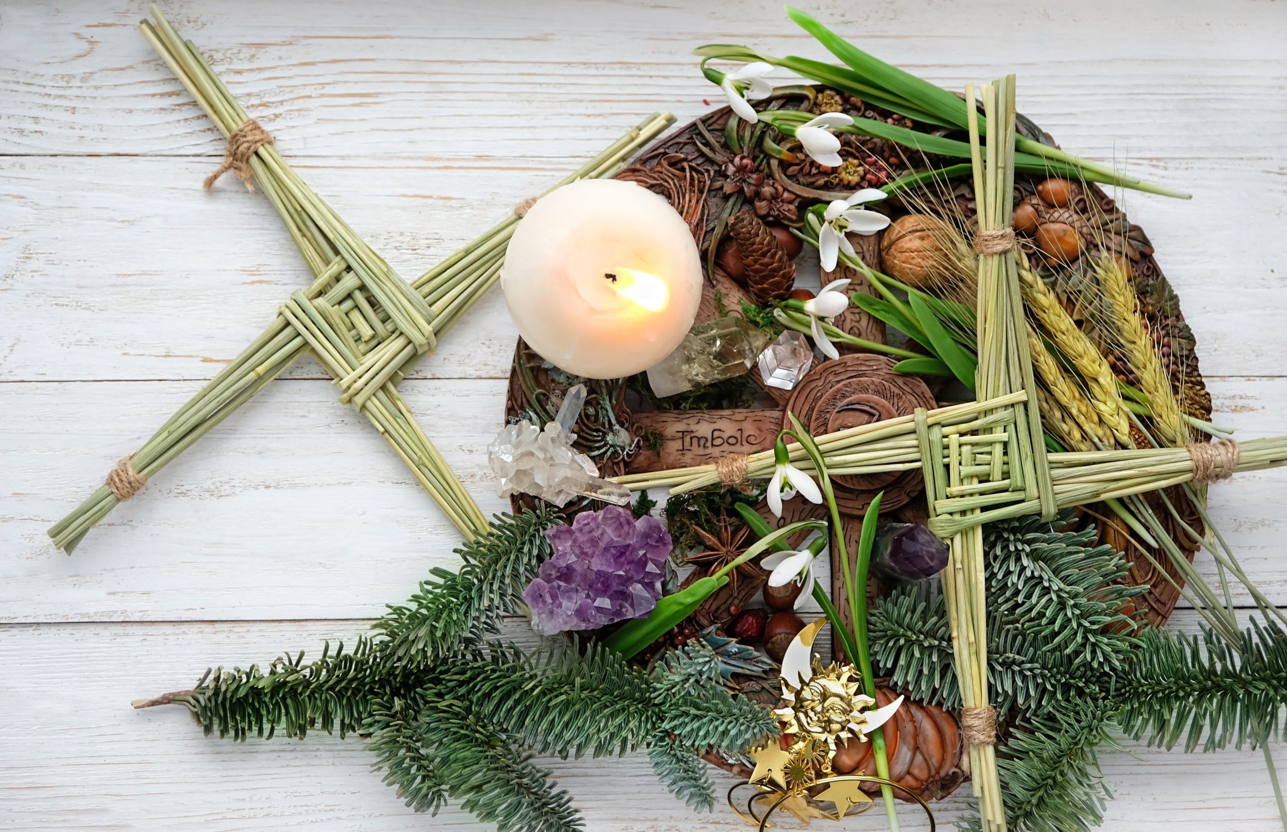 St. Brigid's cross and wheel of ancient Celtic holidays with a lit candle and flowers