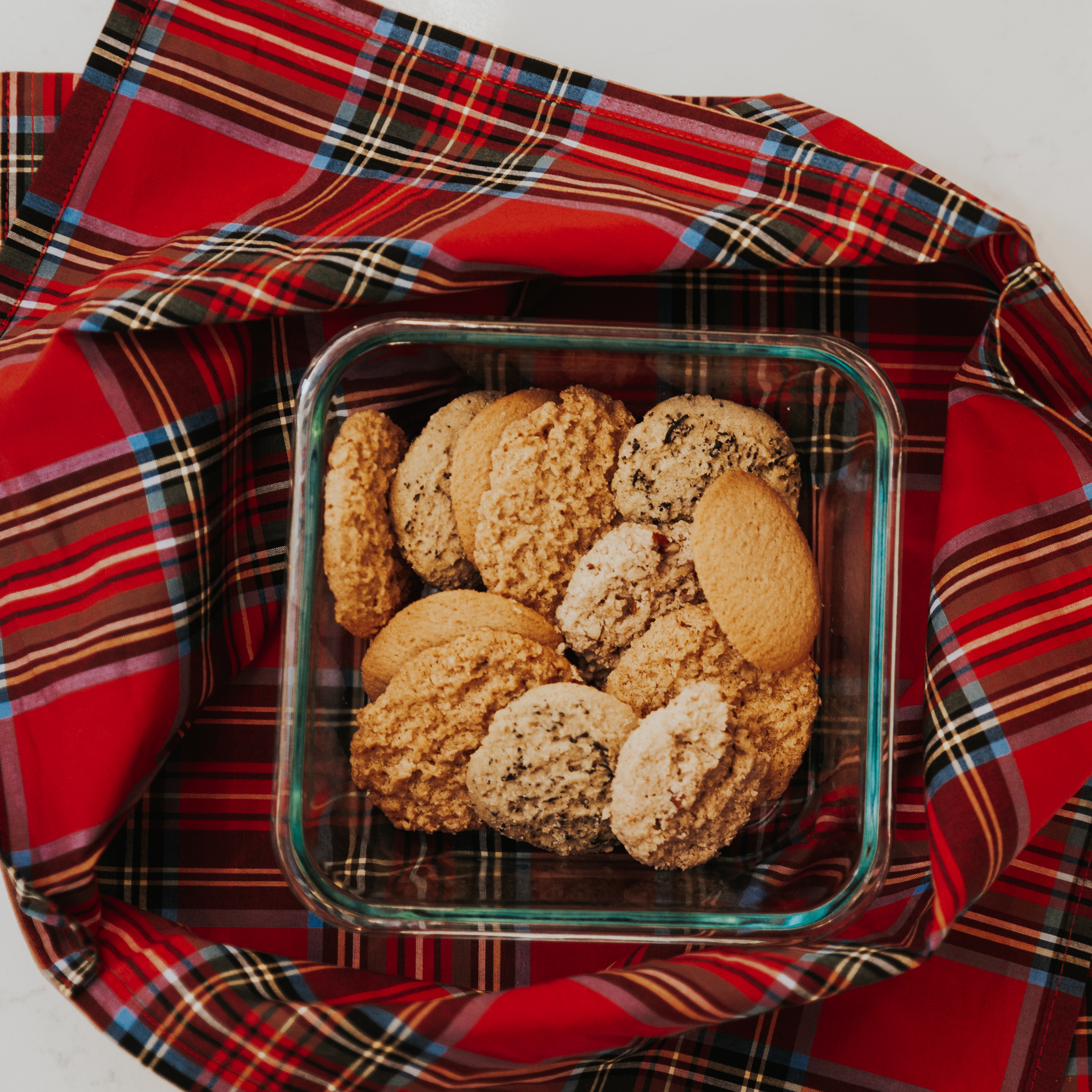 A red tartan bento bag from the Celtic Croft with a dish filled with cookies resting on top.