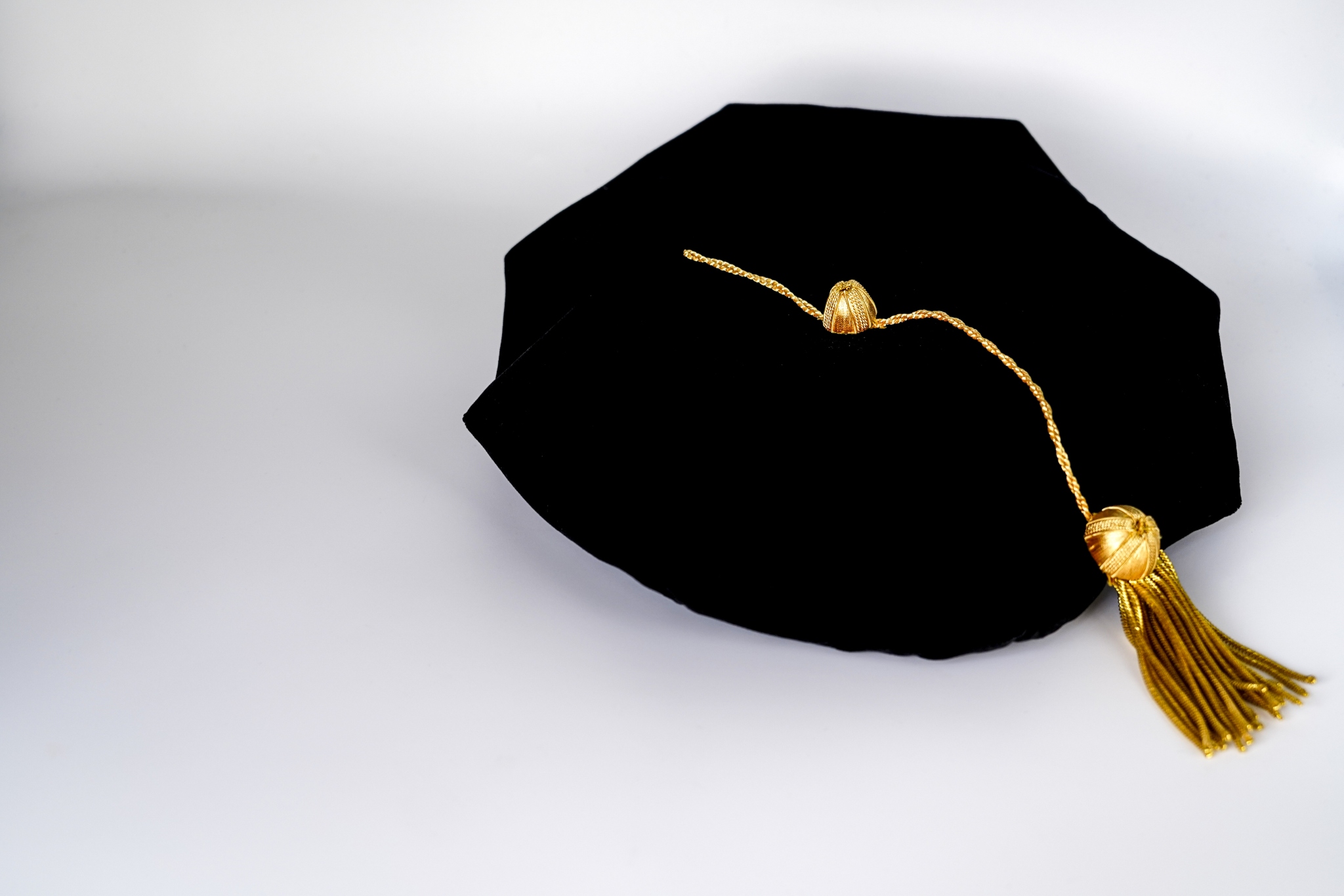 A graduation tam hat with a gold tassel on a white background.